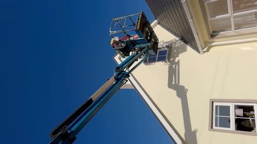 Worker on a Aerial Access Platform Cherry Picker Cleaning House