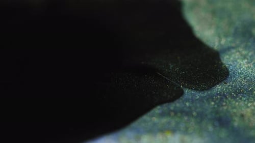 Black Liquid Spreading on Sparkling Blue Surface Macro