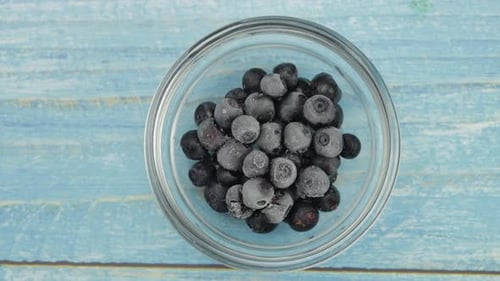 Frozen Blueberries in Bowl on Light Blue Table