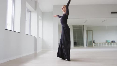 Caucasian female ballet dancer practicing ballet during a dance class in a bright studio