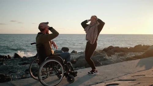 Cheerful Disabled Man and Woman Are Having Fun and Dancing on Sea Embankment