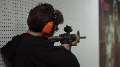 Hombre disparando en el campo de tiro con auriculares protectores