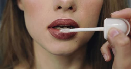 Woman Applies Glossy Lipstick in Close-Up Detail