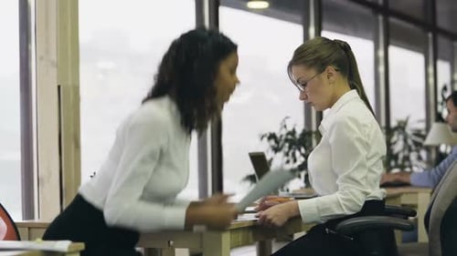 Duas colegas terminam a discussão e continuam trabalhando no projeto separadamente