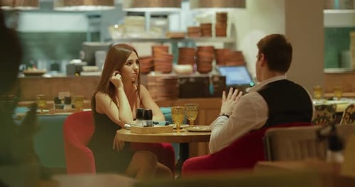 Young Beautiful Woman Sits at a Table with an Elegant Man in an Expensive Modern Restaurant
