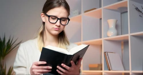 Young Woman Reading Book Indoors in Home