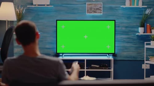 Hombre usando control remoto de TV sobre fondo de pantalla verde