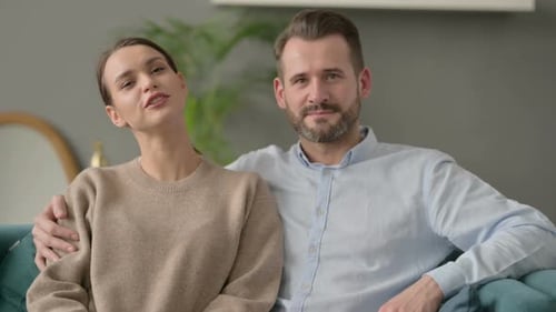 Couple Smiling and Talking on Sofa at Home