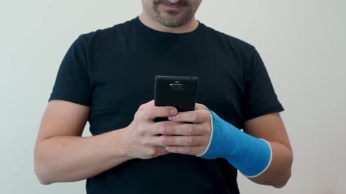 Man with Arm Cast Using Mobile Phone Indoors