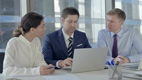 Empresarios ejecutivos compartiendo informe a través de computadora portátil en mesa de oficina