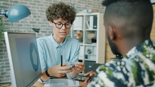 Des collègues heureux discutent d'un modèle d'imprimante 3D regardant un écran d'ordinateur au travail