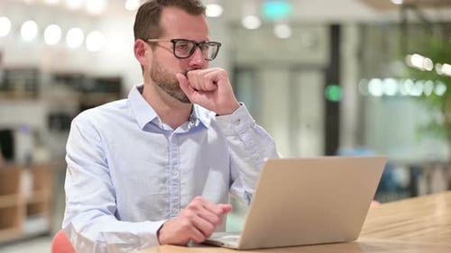 Sick Businessman with Laptop Coughing in Office