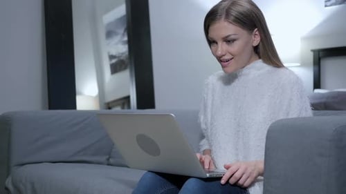Excited Woman Using Laptop at Home Celebrates Success