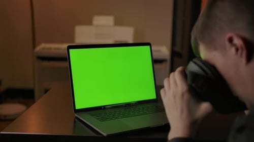 Man Engineer com programação de capacete VR em laptop com tela verde
