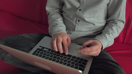 Typing on Laptop Holding Credit Card Indoors