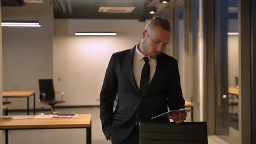 Young Man Looking at Tablet PC at Evening Business Centre.