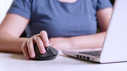 Woman working on laptop and using wireless mouse