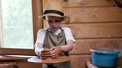 Boy Shaping Clay on Pottery Wheel in Workshop