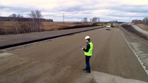 Engineer Using Tablet Inspects Road Construction Site