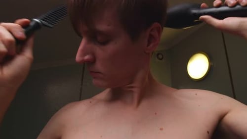 Man Dries Hair with Hairdryer and Comb