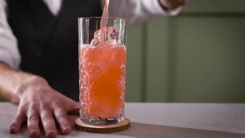 A Close-up in the Night Bar. The Bartender Pours the Finished Cocktail Into the Glass. A Beautiful
