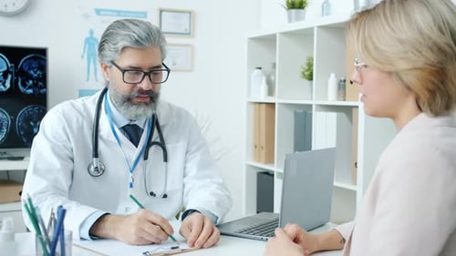 Doctor in White Gown Talking to Young Woman Discussing Treatment in Modern Clinic
