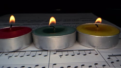 Candles Burning on Sheet Music in Dark Room