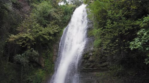 Scenic Waterfall Flowing Down Rock Face Surrounded by Forest