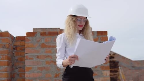 Eine Architektin in Geschäftskleidung steht im obersten Stockwerk unter freiem Himmel auf einer Baustelle