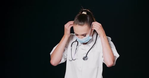 Young Woman Doctor Putting on Protective Surgical Mask