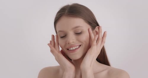 Attractive Woman Touches Face and Smiles in Bright Room