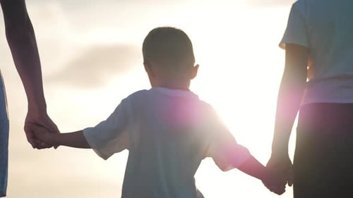 Child Holding Hands with Adults at Sunset Beach