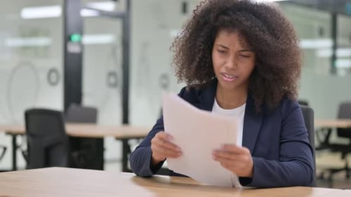 Stressed Woman at Office Desk Reviews Documents