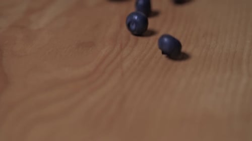 Blueberries Rolling Down a Wooden Board, Closeup. Slow Motion