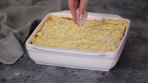 Preparing Delicious Lasagna with Grated Cheese Topping