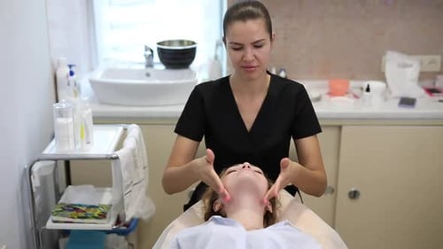 Aesthetician giving woman facial massage in salon