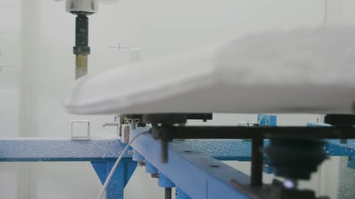 Surfboard being shaped by a machine in a workshop
