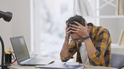 Portrait of Overwhelmed Middle Eastern Teenager Holding Head in Hands Sighing and Taking Off