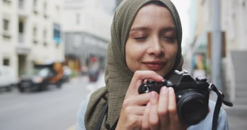 Woman wearing hijab taking photo in the street