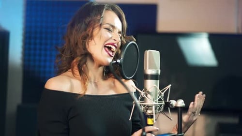 Schöne junge Sängerin, die ein Lied in einem professionellen Tonstudio aufgenommen hat. Weiblicher Gesang