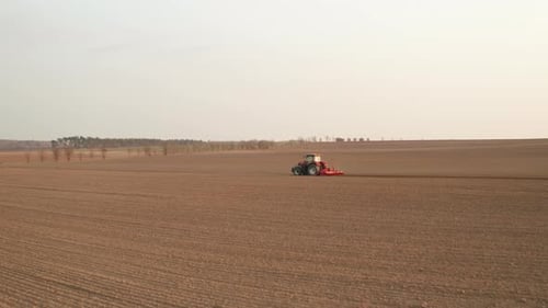 Aerial View of Red Farming Tractor Seeding Wheat at the Field