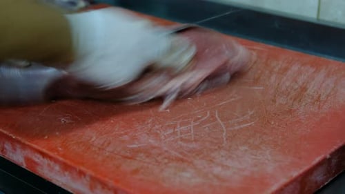Butcher cuts large piece of meat on board