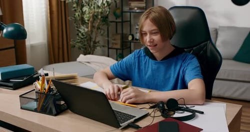 Elementary School Boy Has Lesson with Teacher Remotely Over Internet Child Waves to Laptop Camera to