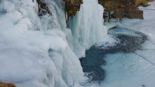 Gros plan du fond de la cascade gelée avec des roches glacées et coulant dans l'eau
