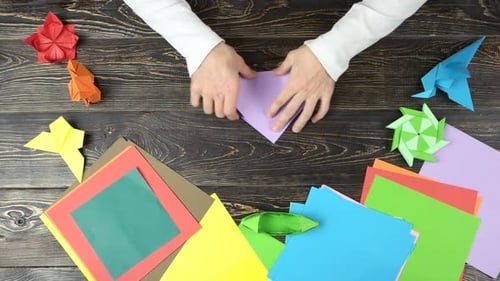Hands Create Origami Art on Wooden Table