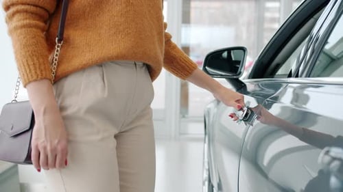 Close-up of Female Buyer Opening Car Door Choosing Automobile in Dealership