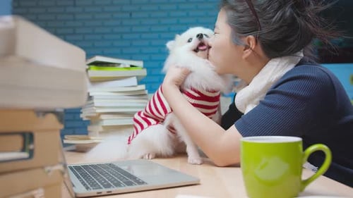 Woman Kisses Dog While Working at Desk