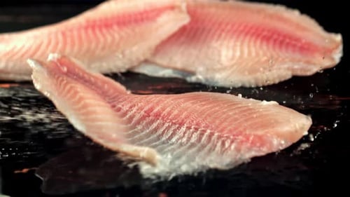 Fischfilets fallen mit Wasserspritzern auf den Tisch