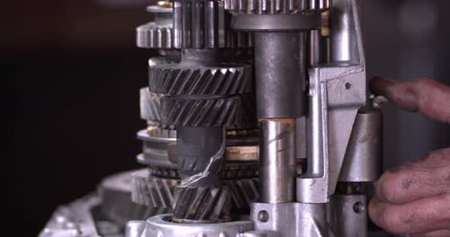 Mecânico de automóveis controla manualmente as engrenagens de transmissão