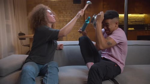 Playful Couple on Sofa with Kitchen Utensils